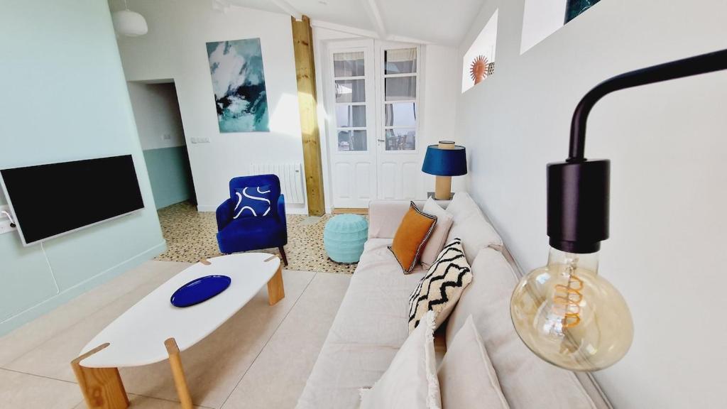een woonkamer met een bank en een tv bij Le Corail, maison cosy avec terrasse in Les Sables-dʼOlonne