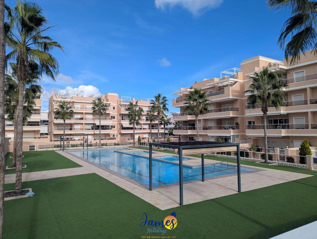 un complesso di appartamenti con piscina e palme di Tropical 3BR Oasis with Pool EB17 a Los Dolses