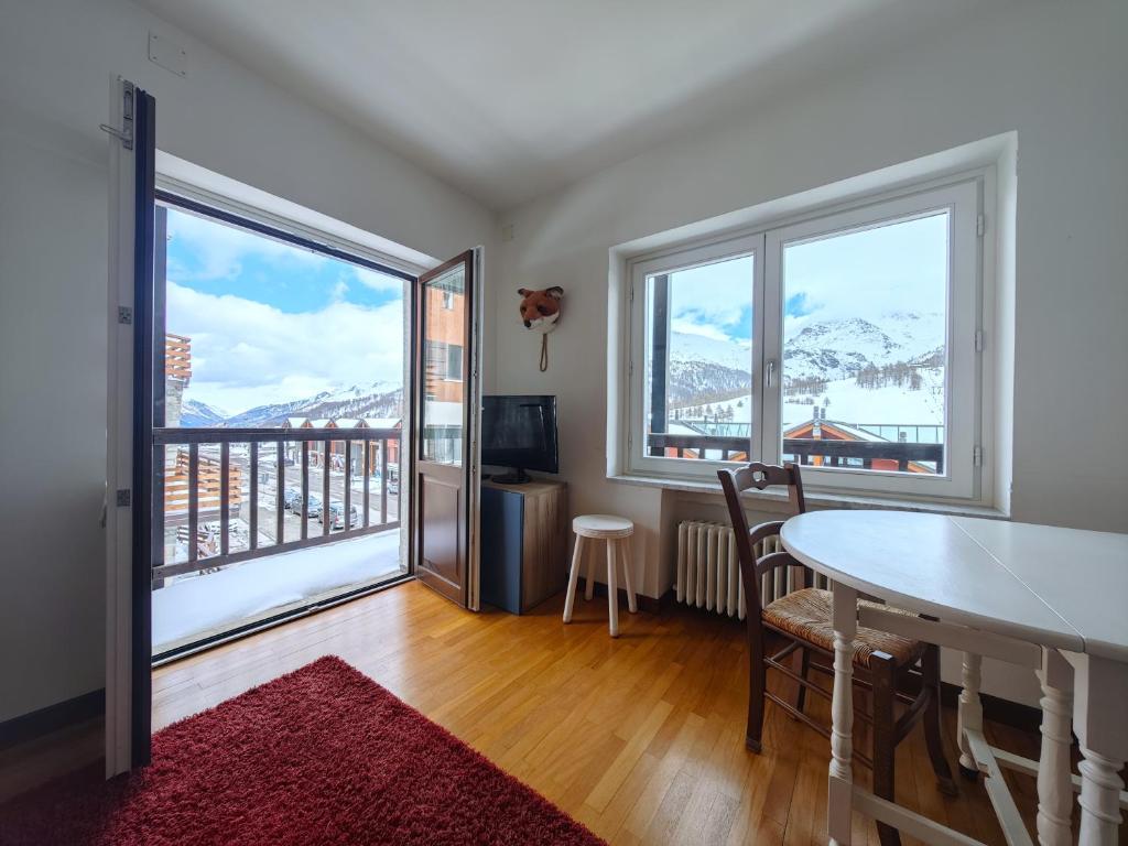 a living room with a table and two large windows at Hostdomus - Fox Suite in Sestriere