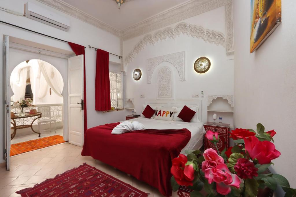 a bedroom with a bed with a red blanket and roses at Riad Morocco Sky in Marrakech