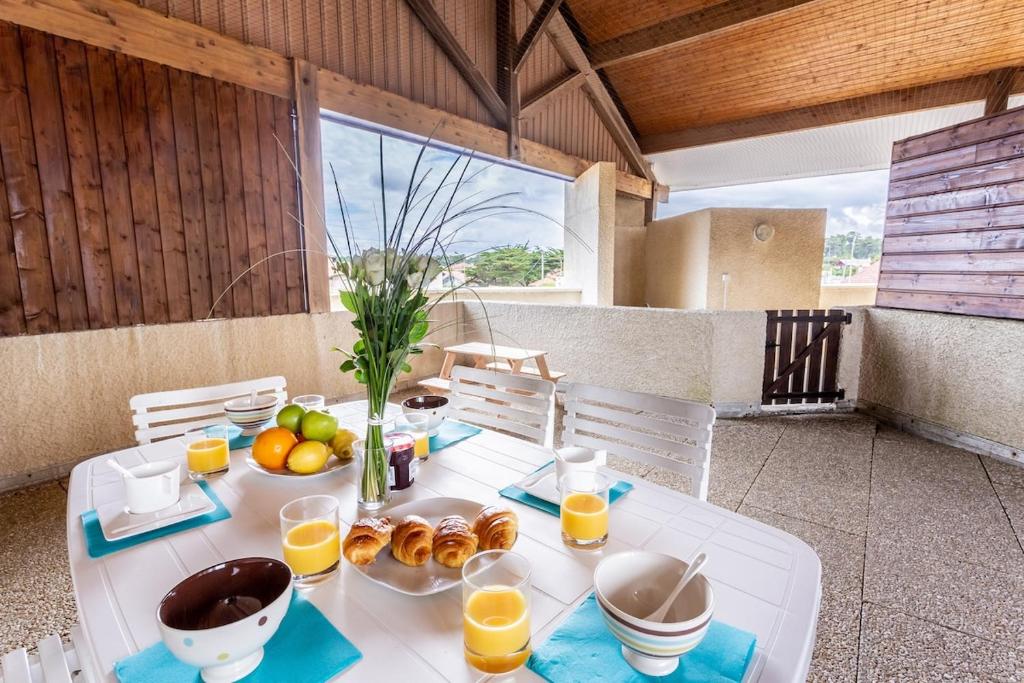 een tafel met eten en sinaasappelsap op een balkon bij L'Echassier in Biscarrosse