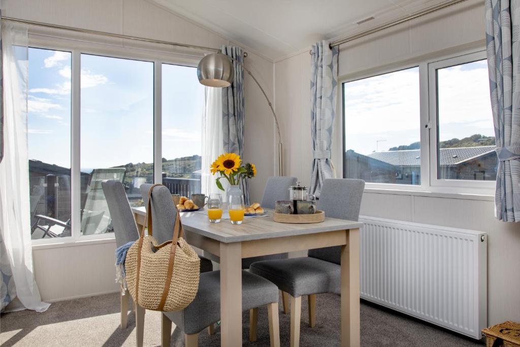 a dining room with a table and chairs and windows at Sea Dreams, Riviera Bay - Brixham in Brixham