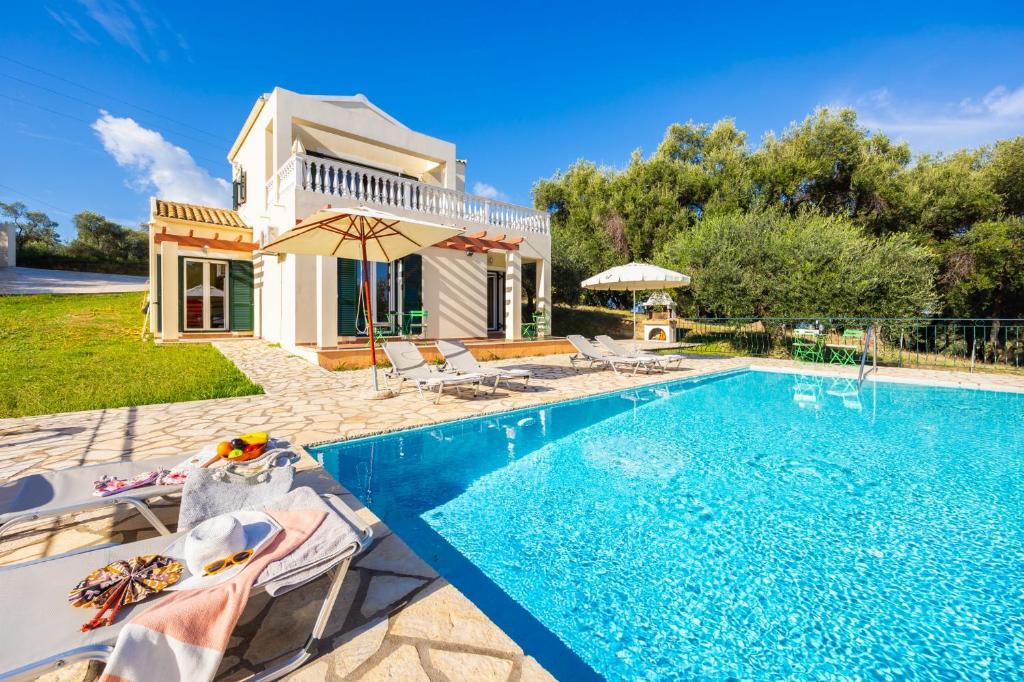 a villa with a swimming pool in front of a house at Villa Iremia in Astrakeri