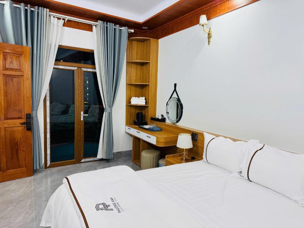 a bedroom with a bed and a desk and a window at Phương Anh Hotel in Mèo Vạc