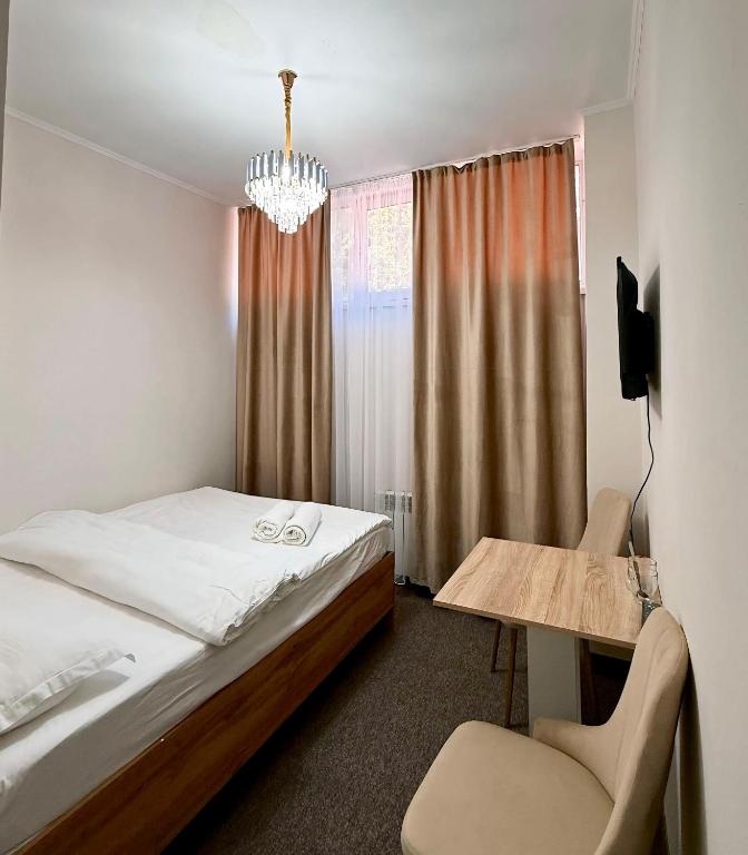 a bedroom with a bed and a table and a chair at GRAND Hotel in Almaty