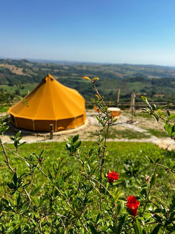 an orange tent in a field with flowers at Glamping & country house Marche Nascoste Gualdo in San Girolamo di Sopra