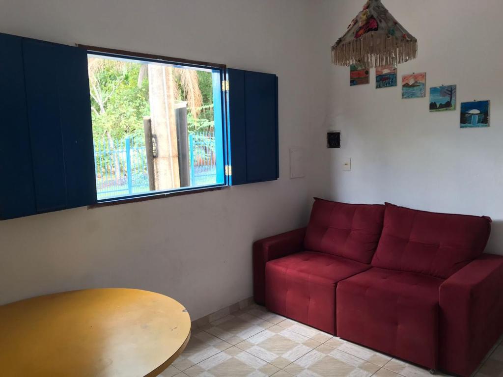 Hostel Diquinha في بيرينوبوليس: غرفة معيشة مع أريكة حمراء وطاولة