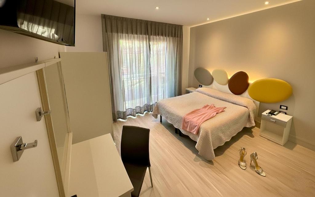 a bedroom with a bed with a pink dress on it at Hotel Belvedere in Sottomarina