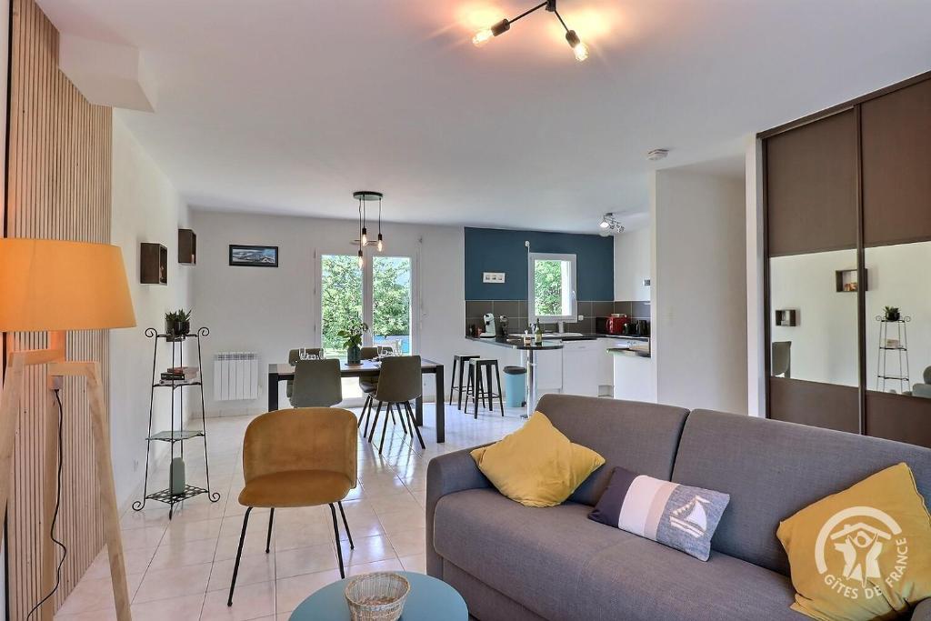 普勒尔蒂La voie verte的一间带灰色沙发的客厅和一间厨房