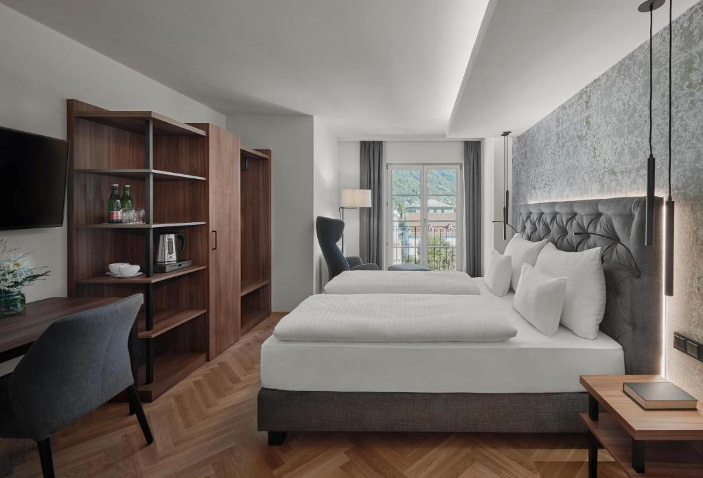 a bedroom with a large bed and a desk and a chair at Hotel Schwarzer Adler Innsbruck in Innsbruck
