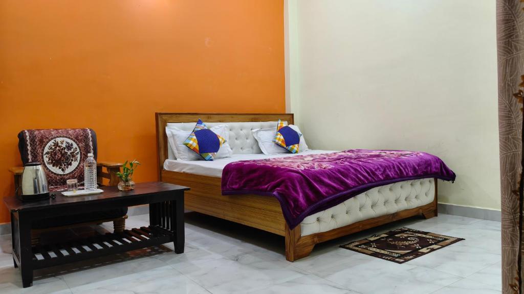 ein Schlafzimmer mit einem Bett mit lila Laken und einem Tisch in der Unterkunft Sri Narayan Home Stay in Ayodhya