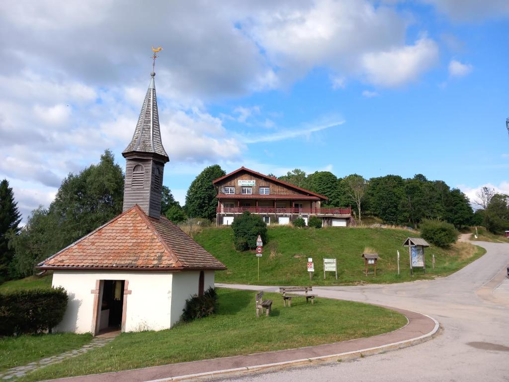 a church with a steeple next to a road at Gîtes BEL'M in La Bresse