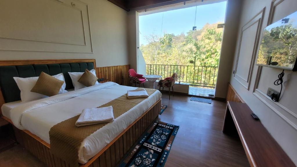 a bedroom with a large bed and a large window at Corbett Mid Forest House By Havensia Stays in Rāmnagar