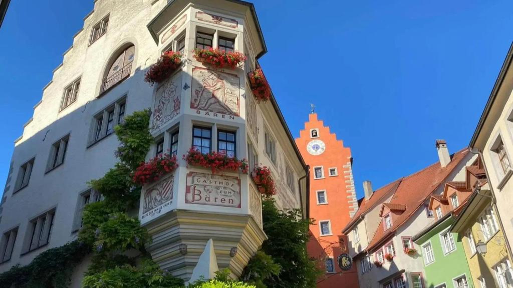 een gebouw met bloemen aan de zijkant met een klokkentoren bij Hotel Bären Meersburg in Meersburg