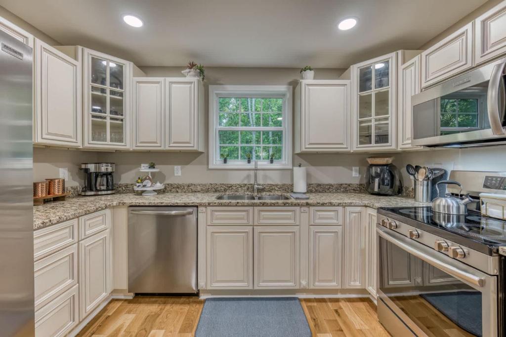 eine Küche mit weißen Schränken und Geräten aus Edelstahl in der Unterkunft Spacious 5BR Home Sleeps 9 Modern Comfort in Jonesborough