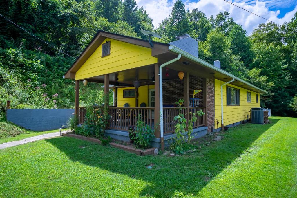 een geel huis met een veranda op een gazon bij Dragon's Lair in Robbinsville