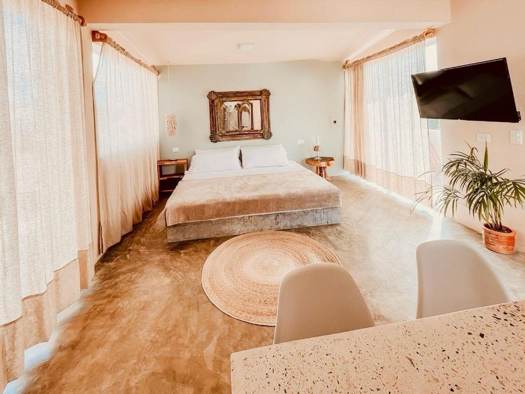 Acogedor estudio con piscina في كانكون: غرفة نوم بسرير وطاولة وتلفزيون