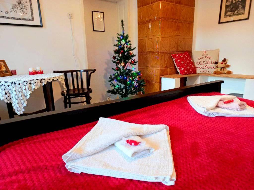 a bedroom with a christmas tree and two towels on a bed at Lankás Vendégház - Hollókő in Hollókő