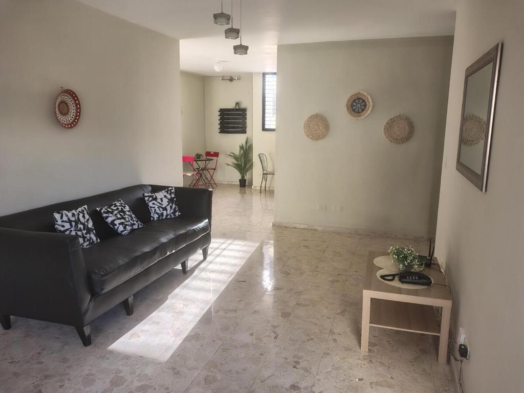 a living room with a black couch and a table at Private and comfortable double room in Santo Domingo