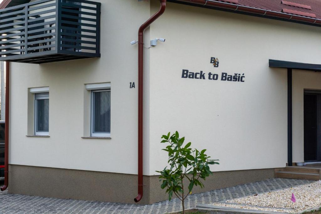 Kuća za odmor Back to Bašić في Mandičevac: مبنى أبيض مع لافتة مكتوب عليها "إلى الأرض"
