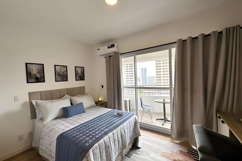 a bedroom with a bed and a large window at 1412 - Studio completo com varanda e vaga in São Paulo