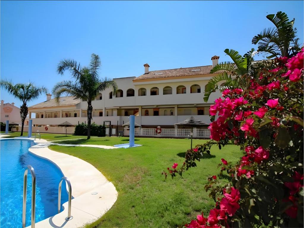 een resort met een zwembad en roze bloemen bij Duplex Penthouse With 4 Bedrooms in Arroyo de la Miel