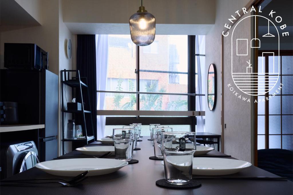 een lange tafel met borden en glazen in een restaurant bij New Open! Central Kobe 最大9名 三宮,元町,中華街,北野へアクセス抜群 長期宿泊設備充実 in Kobe