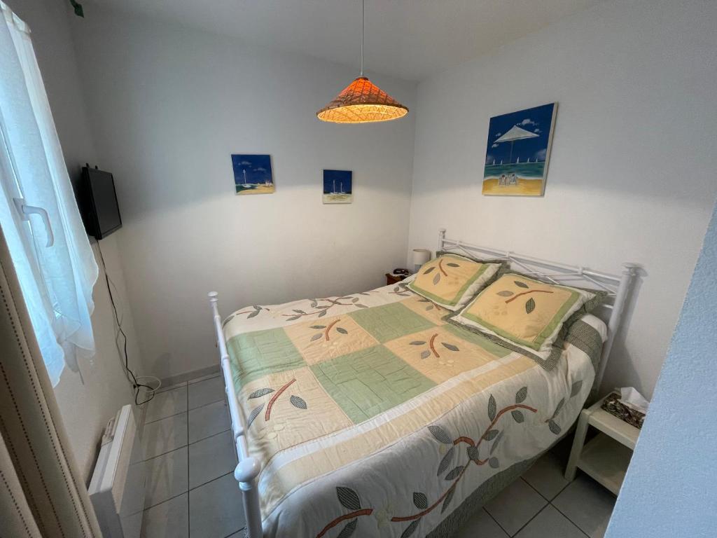 - une petite chambre avec un lit et une couette dans l'établissement Maison dans résidence CopaCabana, à Saint Pierre La Mer