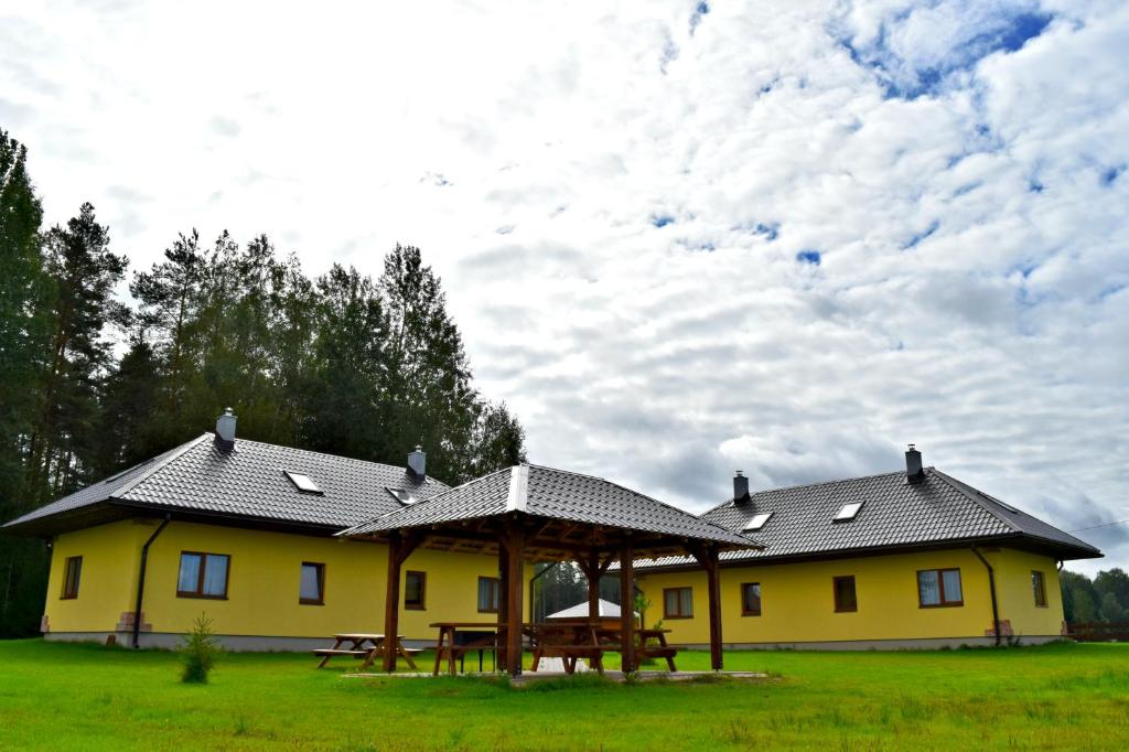 a yellow house with a picnic table in front of it at Holiday Home Četri Vēji in Turkalne