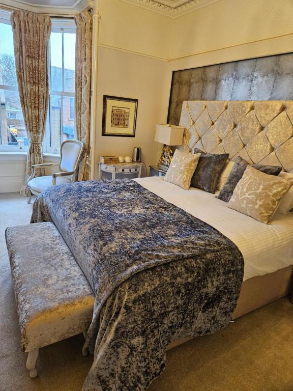 a bedroom with a large bed and a chair at Trinity Boutique B&B in Peterhead