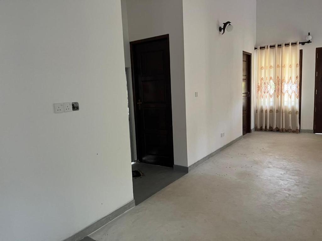 una habitación vacía con paredes blancas y puertas negras en Dissanayaka house, en Tangalle