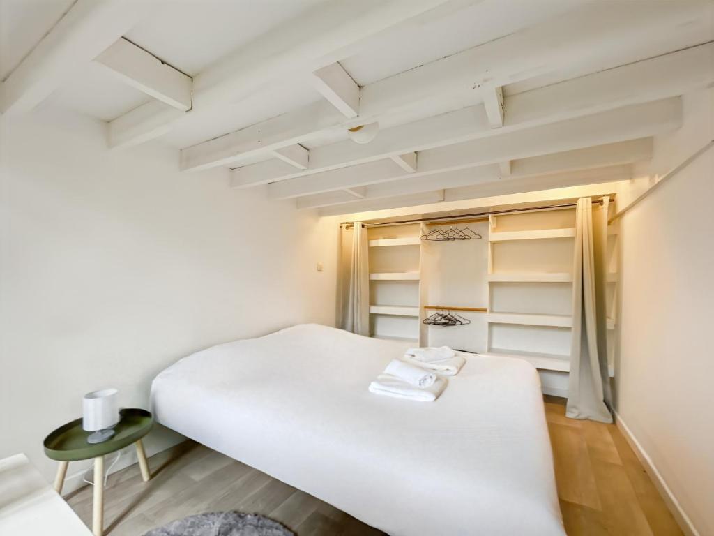 een kleine slaapkamer met een wit bed en planken bij Duplex - Place du Parlement de Bretagne - Hyper Centre de Rennes in Rennes