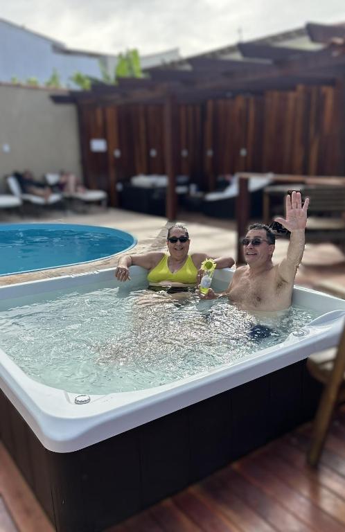 two people in a hot tub in a swimming pool at Pousada Loft Praia dos Anjos in Arraial do Cabo