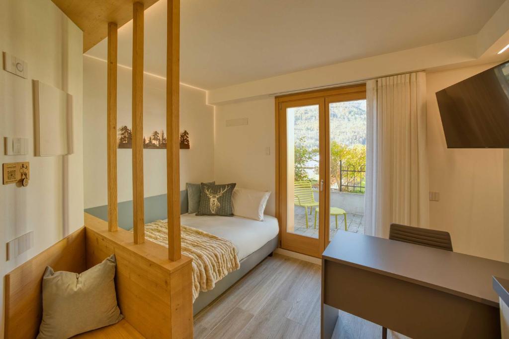 a bedroom with a bunk bed with a desk and a balcony at La Corte Delle Dolomiti in Agordo