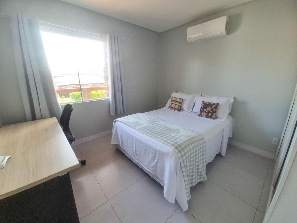 a small bedroom with a bed and a window at Casa no segundo andar na Praia da Cal com ar e sacada in Torres
