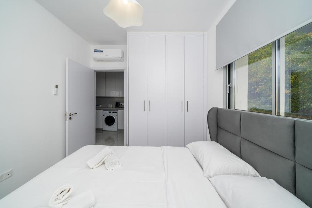 New 2 bedroom flat in Aglantzia في Aglantzia: غرفة نوم بيضاء مع سرير وأريكة