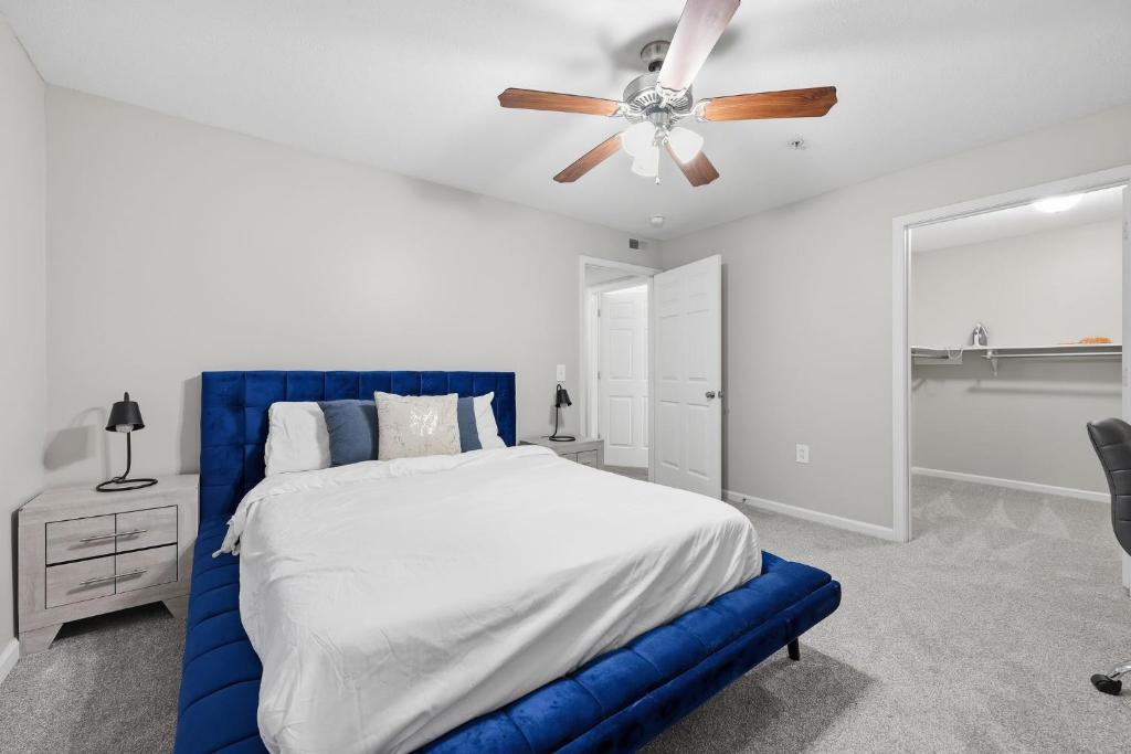 een slaapkamer met een blauw bed en een plafondventilator bij Modern Highland Park 2BR 2BA Stay in Clarksville