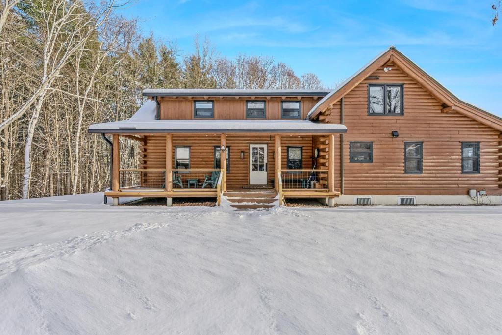 a log home in the snow with a driveway at Log Cabin Fireplace Upper Valley - Wooded Chalet in Hartland