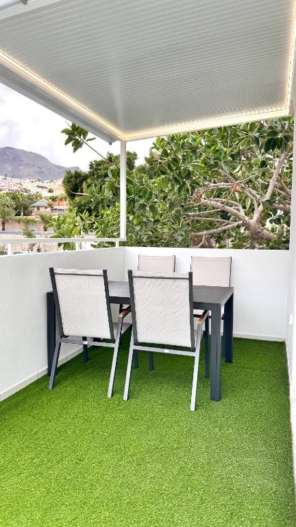 a table and chairs on a balcony with green grass at Las Americas 200 B apartment in Costa de Adeje