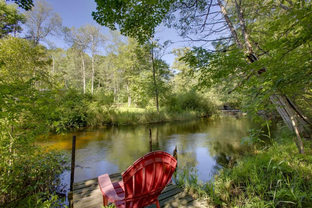 a red boat sitting on the side of a river at Little Manistee Riverfront Cabin with Fire Pit! in Irons