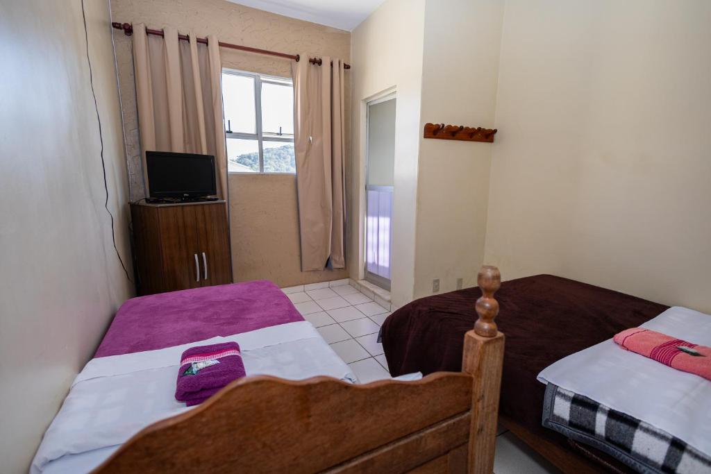 a small bedroom with two beds and a television at Pousada Zacarias in Ouro Preto