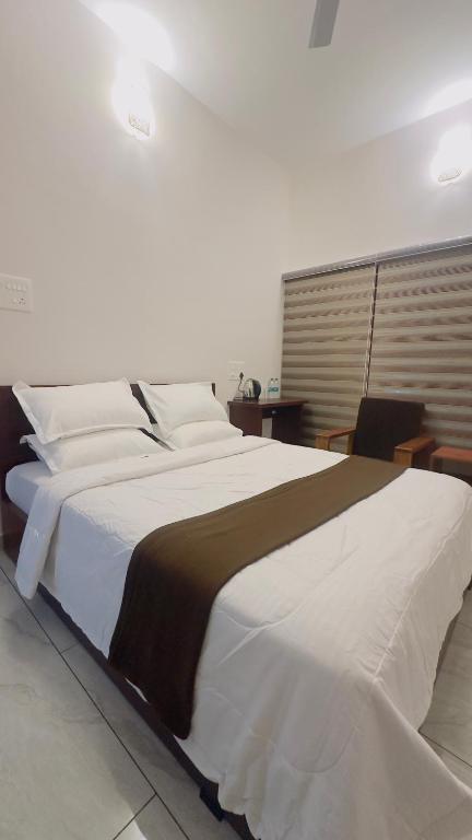 a large bed with white sheets and a brown blanket at TAMARA VISTA Executive Homestay in Varkala