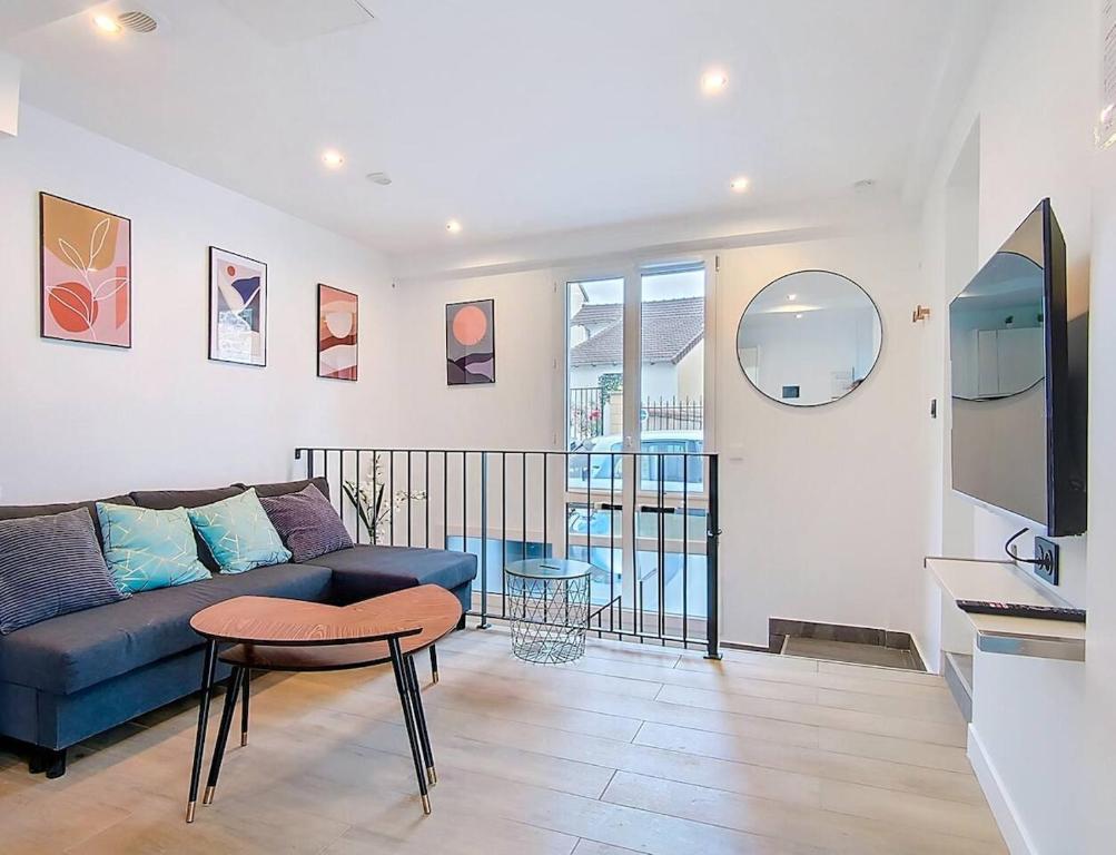 ein Wohnzimmer mit einem blauen Sofa und einem Tisch in der Unterkunft Suite Feel Good - Appartement in Argenteuil