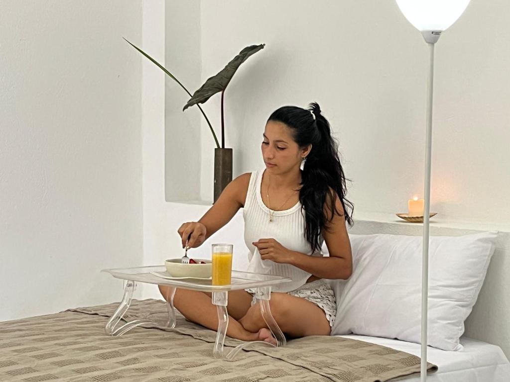 a woman sitting on a bed with a table with a plate of food at Hotel Selva HQ in Palomino
