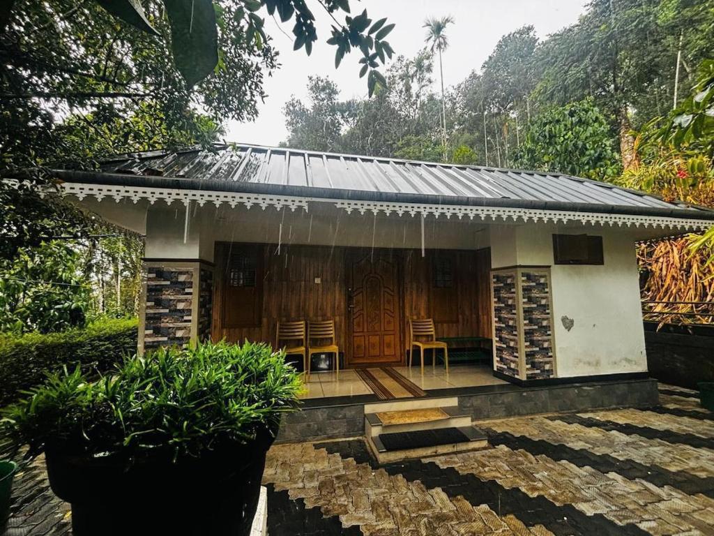 a small house with two chairs in front of it at Munnar Stays - Homestay & Resort in Devikolam