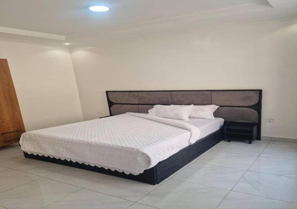 une chambre avec un grand lit dans une pièce dans l'établissement Iwabo Apartments Kigali Airport Kanombe, à Kigali