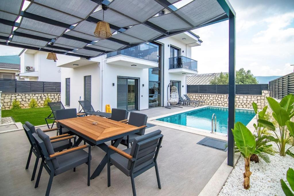 a patio with a wooden table and chairs and a pool at Villa Unique 2 in Fethiye