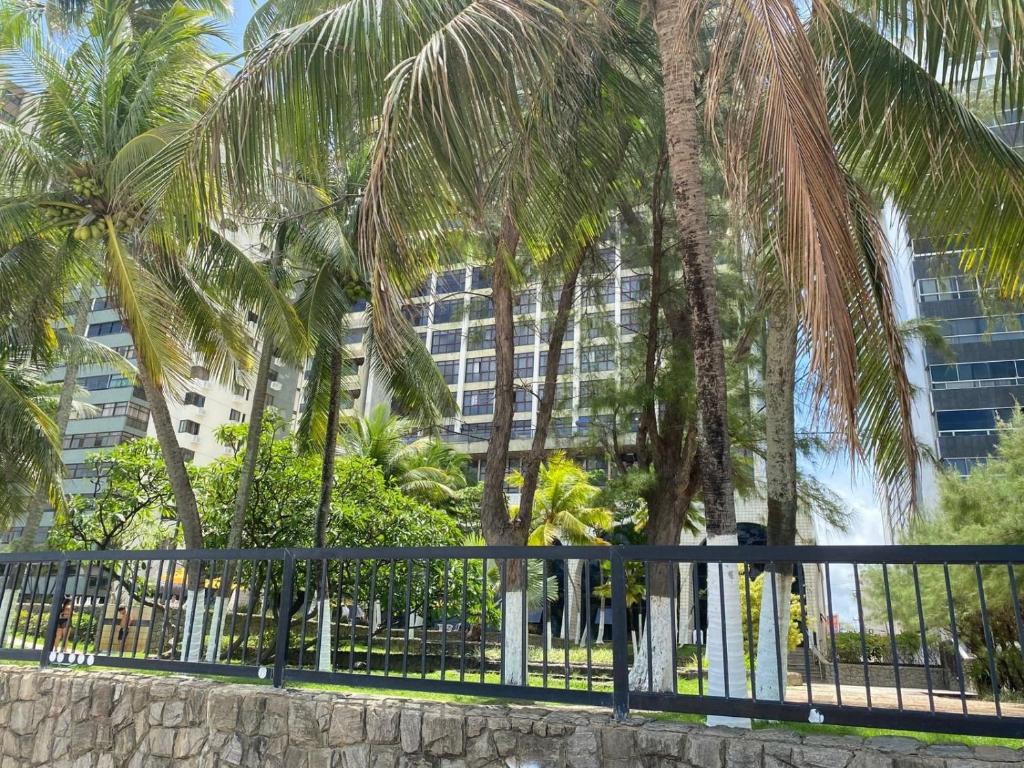 une clôture avec des palmiers devant un bâtiment dans l'établissement Suíte Golden Beach Frente Mar, à Récife