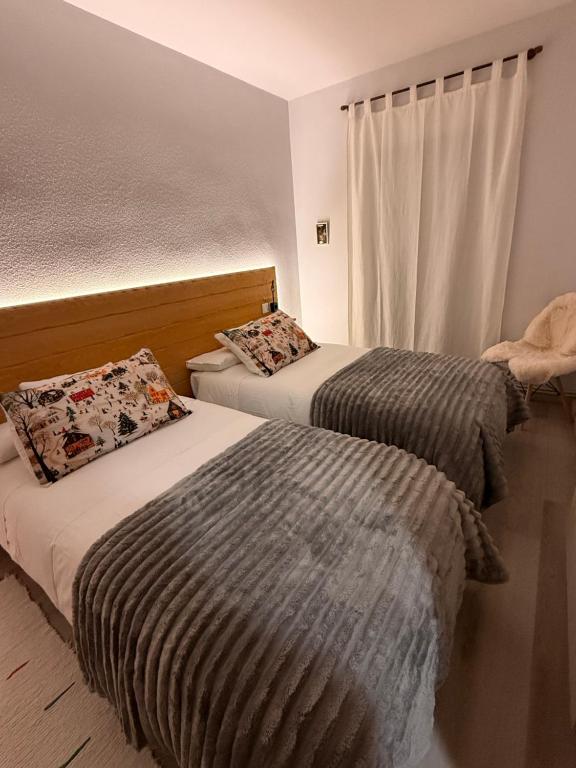 una camera da letto con due letti e una finestra di Apartamento La Pinada a Tramacastilla de Tena