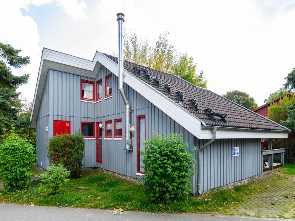 a gray house with red doors and a red window at Gemütliches Ferienhaus im skandinavischen Stil in Granzow